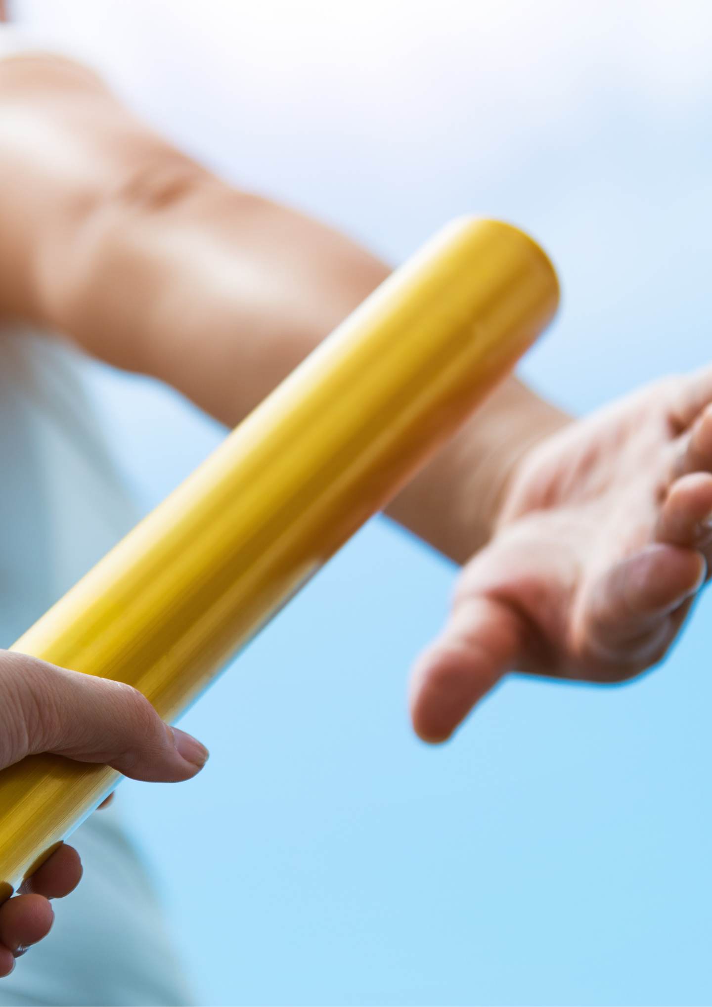 A gold relay baton being passed from one hand to another.
